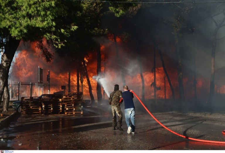 Σε εξέλιξη η μεγάλη φωτιά σε εργοστάσιο ξυλείας στις Αχαρνές  Επεκτάθηκε σε επιχείρηση υποδημάτων